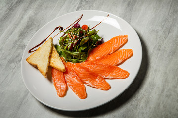 salmon slices served with rucola and tomato salad and toasted bread