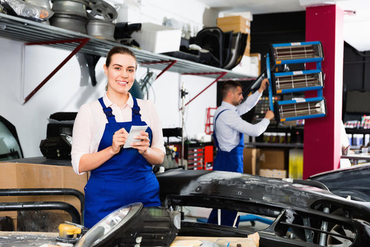 Professional female mechanic recording list of works on car repair in auto repair shop