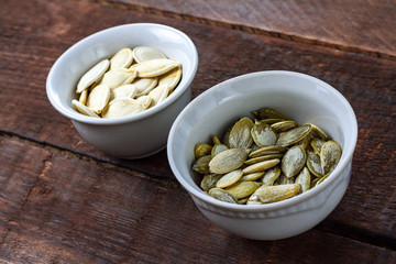 Pumpkin seeds in small saucers on a wooden background