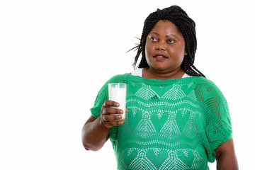 Studio shot of fat black African woman thinking while holding gl