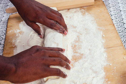 African American male cook chef boasts of pastry hands in flour baking .man`s hands sheets dough with rolling pin bakes cake , the eggs and recipe book on the table. homemade baking - Powered by Adobe