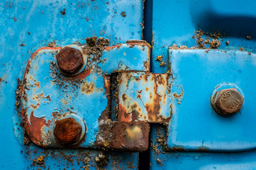 Door hinge of a blue car rusted nuts abandoned