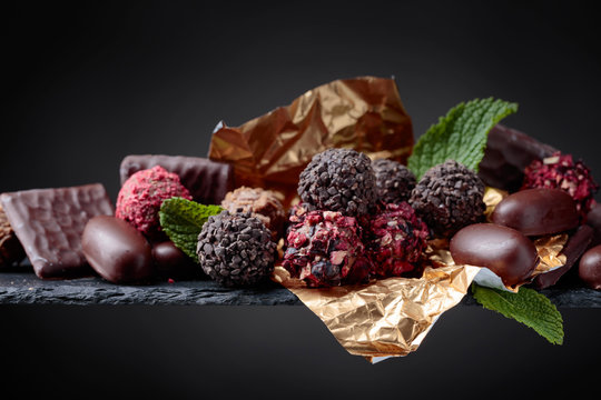 Various chocolates with mint leaves on a black background.