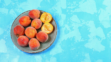 Flat peach in a wooden box on a plate a blue background. Top view. Free space for your text