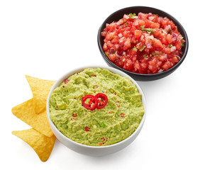 Avocado guacamole and tomato salsa with nacho corn chips isolated on white background
