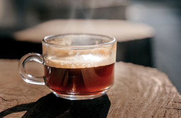 Close up glass cup of coffee on wooden table.