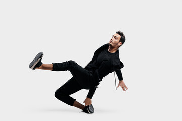 Handsome young dancer wearing a black sweatshirt and black pants is dancing breakdance