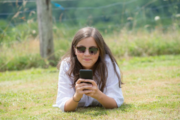 beautiful young girl with sunglasses is using the smartphone