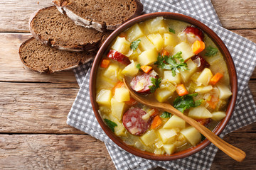 Vegetable thick potato soup with sausages in a bowl close-up on the table. horizontal top view from above