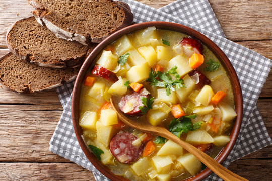 Delicious German potato vegetable soup with sausages in a bowl close-up on the table. horizontal top view from above