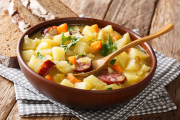 Vegetable thick potato soup with sausages in a bowl close-up. horizontal