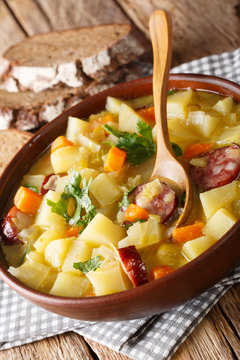 German potato vegetable soup with sausages served with bread close-up. vertical