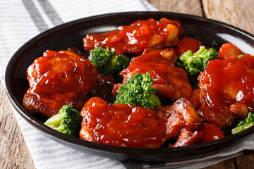 fried chicken thighs with catalina sauce and tomatoes, broccoli close-up on a plate. horizontal