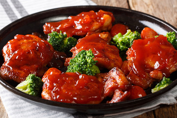 Delicious glazed chicken with spicy sauce and tomatoes, broccoli close-up on a plate. horizontal