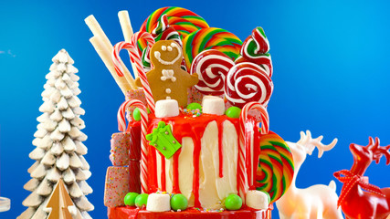On trend festive candyland Christmas drip cake on blue background.