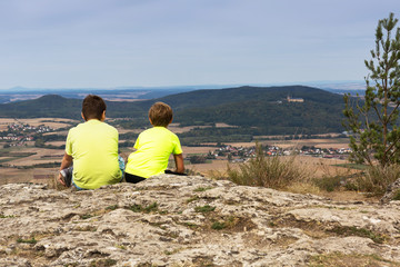 Zwei Jungen sitzen auf einem Felsen und betrachten die Landschaft