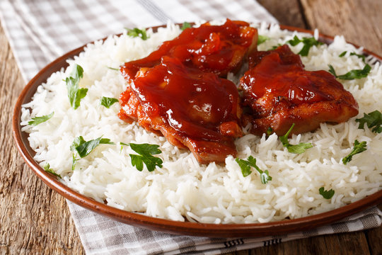 fried glazed chicken thighs with sauce and rice close-up on a plate. horizontal