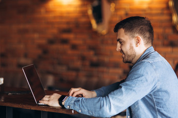 Young programmer working on a laptop in a cafe