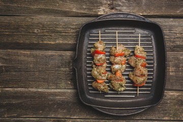 raw chiken meat with vegetables on skewers on grill cast iron pan