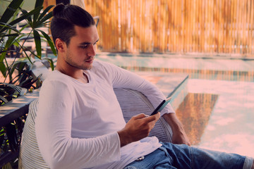 Modern man drinking coffee and using cellphone outdoors.