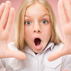 Wow. Beautiful female half-length front portrait isolated on pink studio backgroud. Young emotional surprised teen girl standing with open mouth. Human emotions, facial expression concept. Trendy