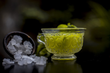 Iced cucumber and mint tea on wooden surface in a transparent cup with slices of cucumber and raw cucumber,mint leaves,sugar and honey with green tea in a separate glass cup.