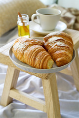 Croissants and coffee for breakfast in bed. Concept of cozy holiday
