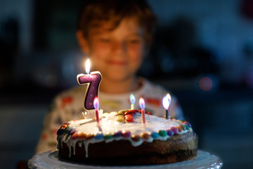 Adorable happy blond little kid boy celebrating his 7 birthday.
