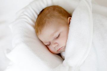 Cute little newborn baby girl sleeping wrapped in blanket