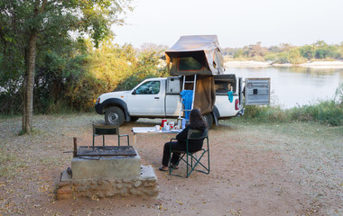 Woman relaxing in front of het offroad 4x4 vehicle with tent in the roof
