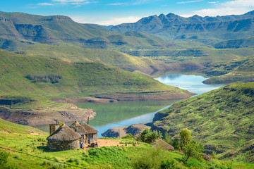 Lesotho traditional hut house homes in Lesotho village in Africa. Beautiful scenic landscape of village in daytime with typical huts built by villagers by the lake of Mohale Dam - obrazy, fototapety, plakaty