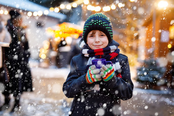 Little cute kid boy drinking hot children punch or chocolate on German Christmas market. Happy...
