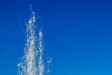 Water jet from a fountain in a park, with the blue background of the sky.