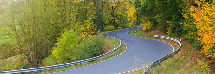 Winding Road in the autumnal forest . Nature background.