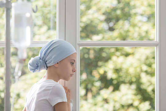 Sad Sick Child With Cancer Wearing Blue Headscarf During Treatment