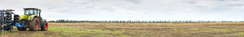 Fototapete Tractor working on the farm, a modern agricultural transport, cultivation of fertile land, tractor on cloudy sky background, agricultural machine