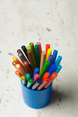 Set of markers in a plastic cup  on stone background. Top view. concept