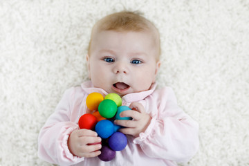 Cute baby girl playing with colorful wooden rattle toy