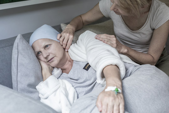 Daughter supporting sick mother with headscarf after chemotherapy