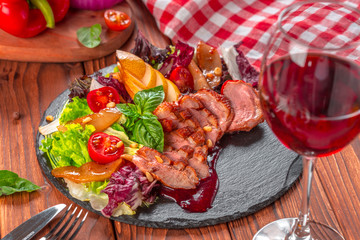 Tasty sliced roast duck breast with fresh vegetable salad closeup on a plate.