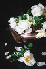 Naklejka na ściany i meble Copper teapot with white flowers on a black background