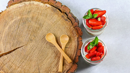 homemade, exquisite dessert tiramisu in glasses decorated with strawberry, mint, On a wooden stump. Authentic lifestyle image. copy space