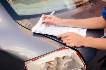 Close-up of filling out the insurance form near the damaged car.