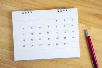 Calendar page with pen on wooden desk table