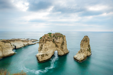Obraz premium Rouche skały w Bejrucie w Libanie w pobliżu morza i podczas zachodu słońca. Pochmurny dzień w Bejrucie w Libanie na Pigeon Rocks na Morzu Śródziemnym.