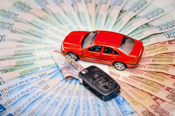 Toy car with a real key, lie on a pile of banknotes of the Russian Federation. The concept of buying a new car.
