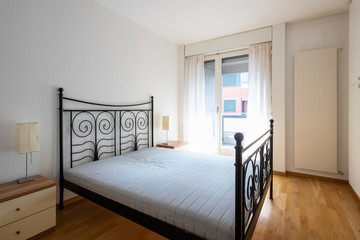 Bedroom with parquet and large wardrobe. Apart from the bed the room is empty. Nobody inside