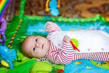 Cute adorable newborn baby playing on colorful toy gym