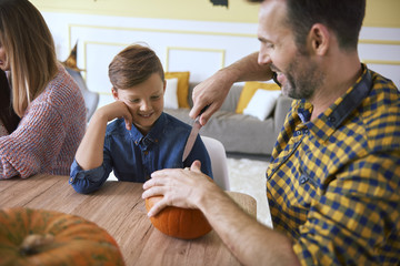 Father helping son in carving pumpkins