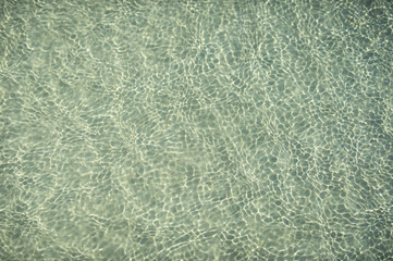 Tropical blue-green waters background in shallow seas with small waves in bright sunlight